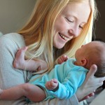 Young Mother Smiling at Newborn Baby in Home Nursery