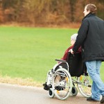 old senior woman in wheelchair with careful son