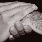 young man holding the hand of an old man, in black and white
