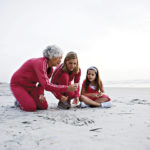 Grandmother with her daughter and granddaughter collecting stones at the beach