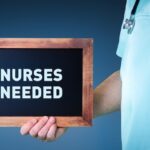 Nurses,Needed.,Doctor,Shows,Sign,(board),With,Wooden,Frame.,Background