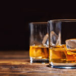 Two,Glasses,Of,Whiskey,With,Ice,Cubes,Served,On,Wooden